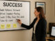 Factoring Broker updating her dry erase board.